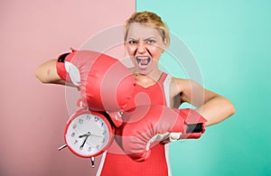 Punching a clock. time for success. win the day. angry woman boxing gloves. girl boxer hold alarm clock. morning energy