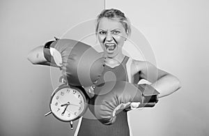 Punching a clock. time for success. win the day. angry woman boxing gloves. girl boxer hold alarm clock. morning energy