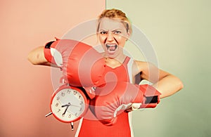 Punching a clock. time for success. win the day. angry woman boxing gloves. girl boxer hold alarm clock. morning energy