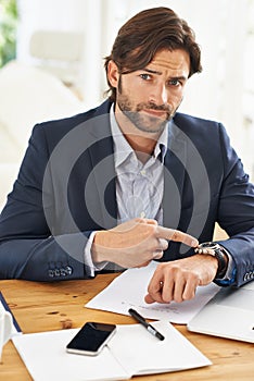 Punctuality is crucial in this office. A handsome businessman checking the time on his watch at his desk.