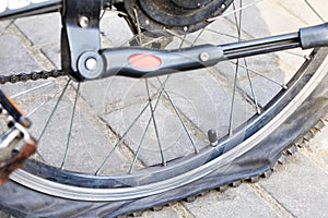 A punctured bicycle wheel on the background of paving slabs. Closeup