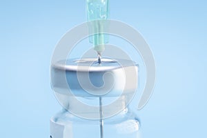 Punctured syringe in a bottle to put a vaccine on blue background