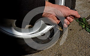 Punctured tire from crash with curb. damaged sidewall and aluminum wheel rim. man with a knife from military special forces shows