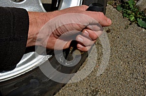 Punctured tire from crash with curb. damaged sidewall and aluminum wheel rim. man with a knife from military special forces shows photo