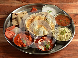 Punjabi Veg Thali from an indian cuisine, food platter consists variety of veggies, lentils, jeera rice, roti, sweet dish, curd,