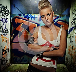 Punk girl with graffiti painted gateway behind her