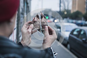 Punk guy looking at himself in a shattered mirror