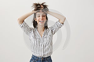 Punks not dead. Portrait of funny attractive woman with sense of humour lifting up hair with hands, looking like rock n