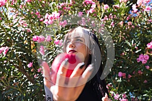 Punky girl with blonde and brunette hair holds a red apple in her hands and stares at it. The girl is a witch from the fairy tale