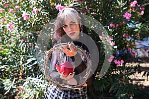 Punky girl holding a red apple and a crown of thorns in her hands. represents the apocalypse from the beginning with adam and eve