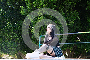 Punky girl is sitting with her skateboard on a skateboarding platform. The girl is resting. Concept skating or skateboarding