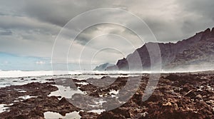 Punta del Hidalgo, Tenerife, Espania - October 27, 2018: Panorama of the rocky beach of Punta de Hidalgo and the waves breaking at photo