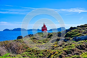 Lighthouse In Landscape. The iconic red lighthouse at Punta Robaleira. Cabo Home, Cangas, Galicia, Spain photo