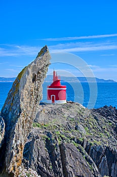 Lighthouse In Landscape. The iconic red lighthouse at Punta Robaleira. Cabo Home, Cangas, Galicia, Spain photo