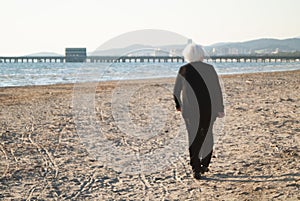 Puntone Scarlino, Maremma Tuscany, Italy. Senior woman walking on the beach