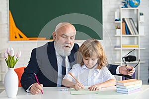 Pupil child lesson. School senior teacher. Education concept. Old grandfather teacher with schoolboy in classroom.
