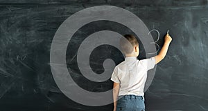 Pupil in class at a math lesson writes on a chalk board with chalk. Elementary school math lesson. Learning concept