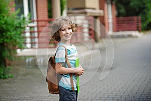 The pupil of elementary school stand on a schoolyard and smiles.