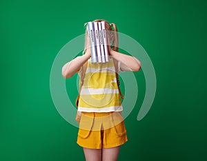 Pupil holding schoolbooks in front of face