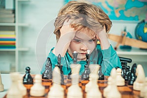 Pupil kid thinking about his next move in a game of chess. Clever concentrated and thinking child while playing chess