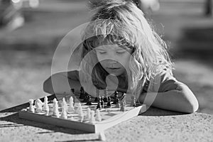 Pupil kid thinking about his next move in a game of chess. Concentrated little boy sitting at the table and playing