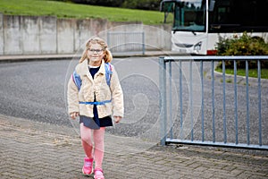 Pupil of primary school. Little girl with backpack near building outdoors. Beginning of lessons. First day of fall