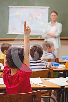 Pupil raising hand during geography lesson in classrorm