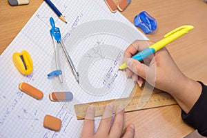 Pupil& x27;s hand close-up solve a geometry example in a notebook.