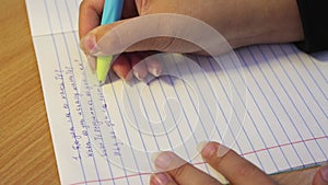 Pupil's hands close-up in poor handwriting write in native English.