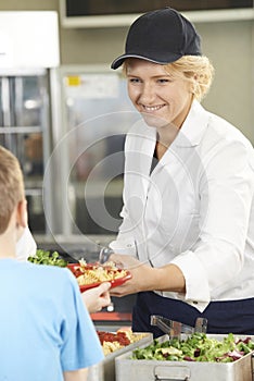 Pupil In School Cafeteria Being Served Lunch By Dinner Lady