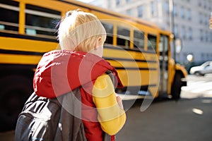 Pupil with schoolbag with yellow school bus on background