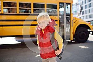 Pupil with schoolbag with yellow school bus on background