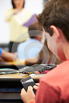 Pupil Sending Text Message On Mobile Phone In Class