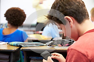 Pupil Sending Text Message On Mobile Phone In Class