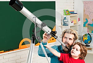 Pupil watching stars with a teacher. Astronomy telescope. Happy cute industrious child is sitting at a desk indoors