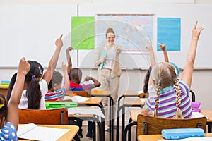 Pupils raising hand during geography lesson in classroom