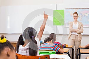 Pupils raising hand during geography lesson in classroom