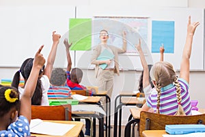 Pupils raising hand during geography lesson in classroom