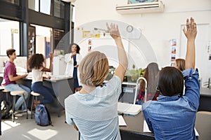 Pupils raising hands in a high school science lesson