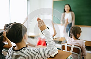 Pupils raising their hands during class at the elementary school, closeup. Education, learning and people concept