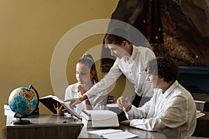 Pupils at school study and communicating with classmates at geography lesson. Education concept. Children reading book