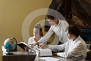 Pupils at school study and communicating with classmates at geography lesson. Education concept. Children reading book