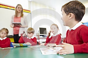 Pupils Sitting At Table As Teacher Stands By Whiteboard