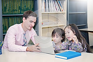 Pupils studying with teacher using computer device in classroom