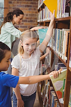 Pupils taking books from shelf in library