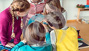 Pupils and teacher in geography class studying a globe