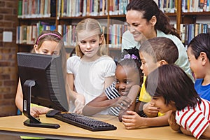 Pupils and teacher in the library using computer