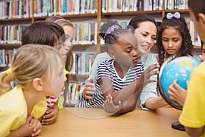 Pupils and teacher looking at globe in library