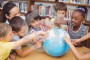 Pupils and teacher looking at globe in library