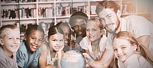 Pupils and teacher looking at globe in library